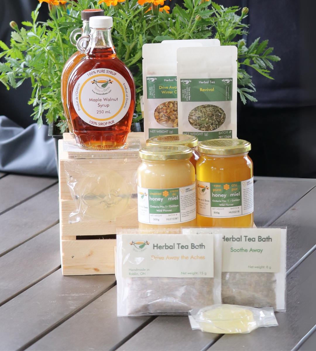 Teas and Bees products. Picture shows honey and tea products next to flowers on a gray table.