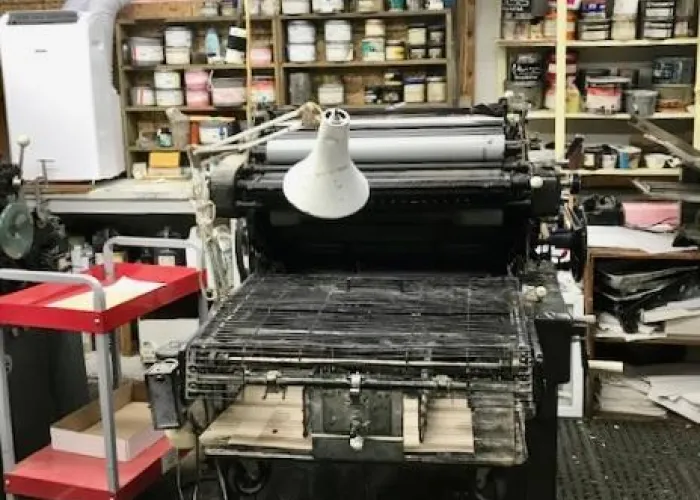 View of a printing press inside a print business with printing equipment in the background