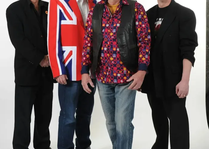 White background, white floor, four band members of british invasion standing together looking at camera